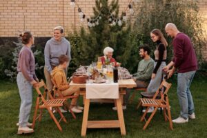 family sitting around table in garden sharing food
