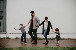 family walking along street holding hands with kids pulling